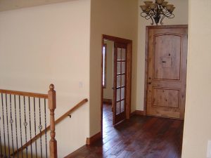 this shows the interior entryway of a custom home with wood floors.